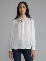 Female wearing white blouse with tie neck
