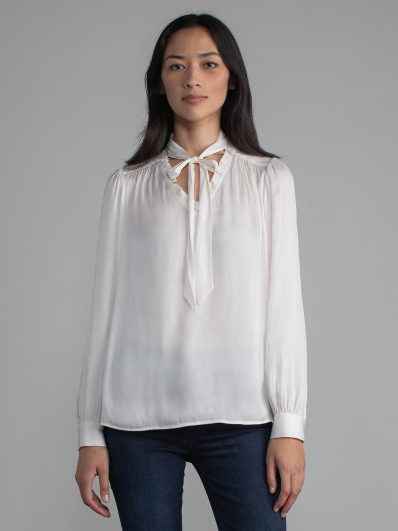 Female wearing white blouse with tie neck