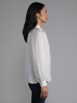 Female wearing white blouse with tie neck
