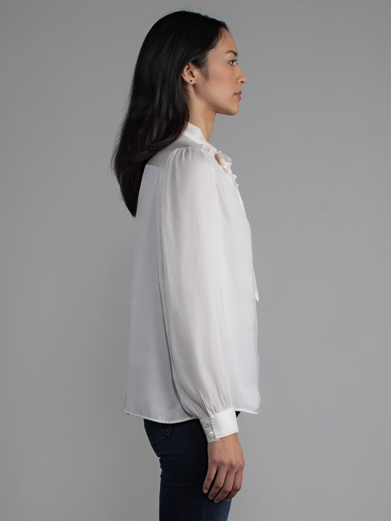 Female wearing white blouse with tie neck