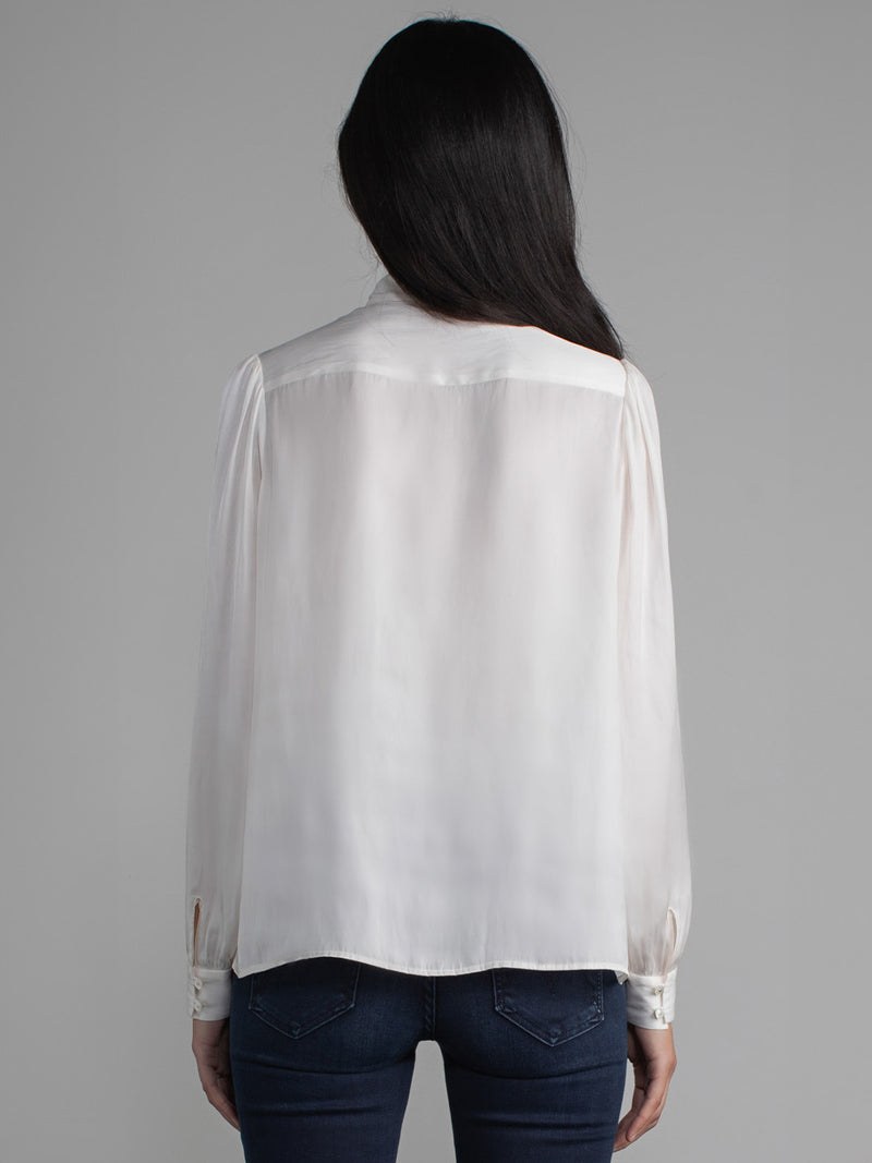 Female wearing white blouse with tie neck