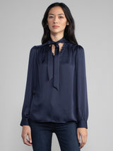 Female wearing blue blouse with tie neck