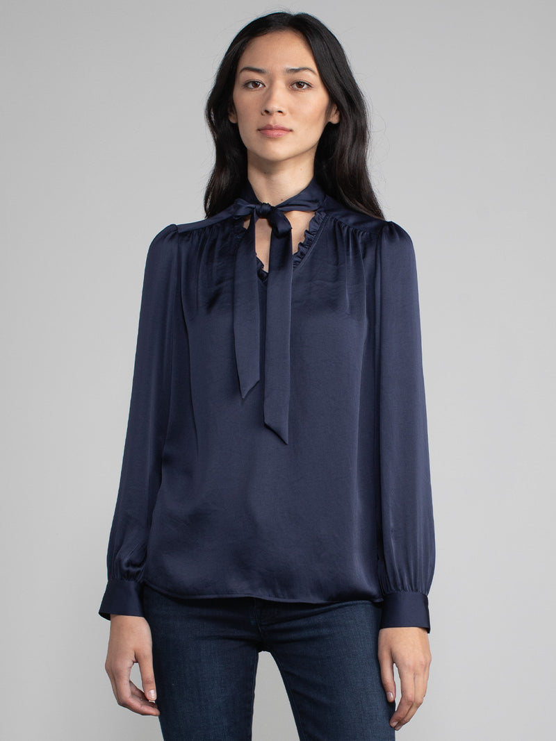 Female wearing blue blouse with tie neck