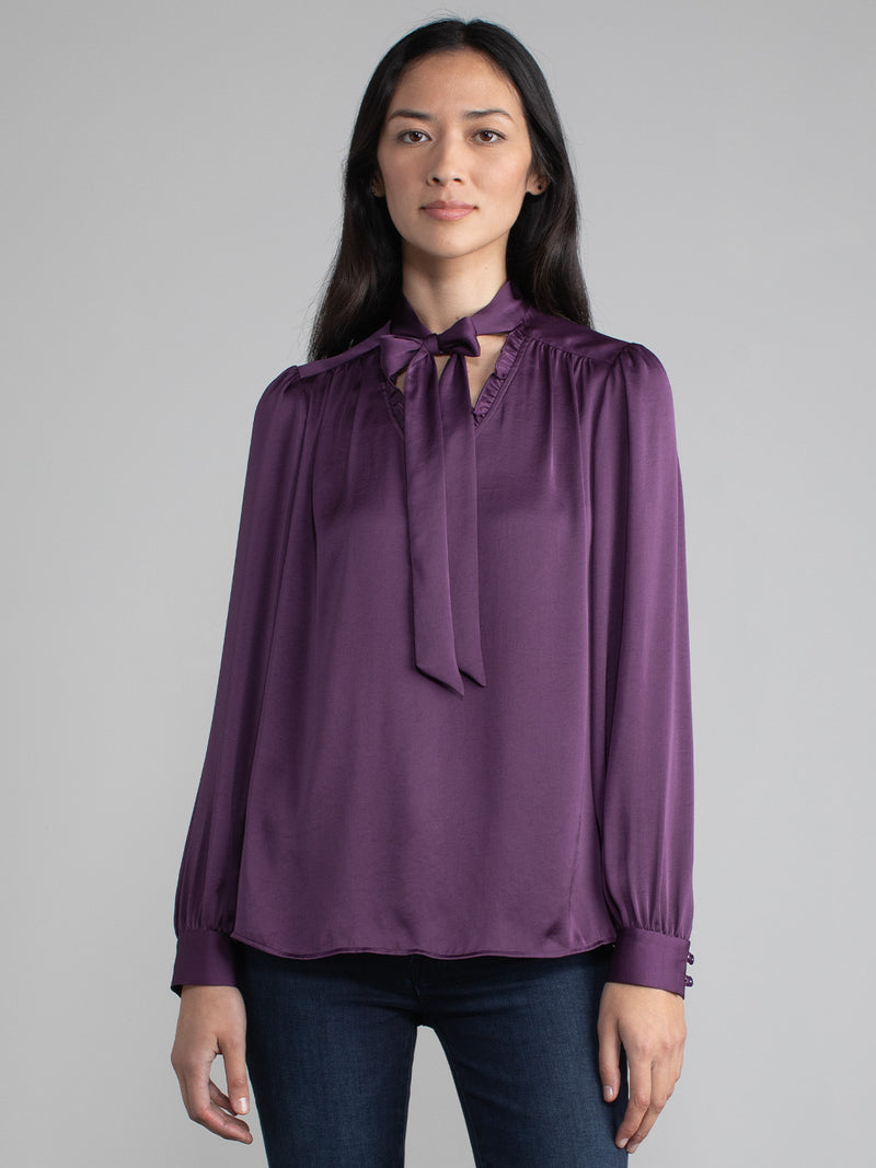Female wearing purple blouse with tie neck