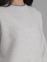 Female wearing white waffle stitched pullover.