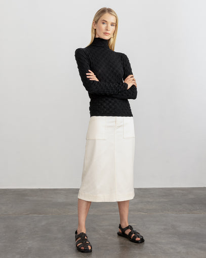 Woman wearing Dimensional T-Neck in Black and the Ophelia Skirt in Muslin made by Margaret O'Leary with black sandals. 