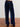 Navy blue velvet pants on a wooden floor with a white wall background