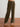 Olive green velvet pants on a wooden floor with a white wall background
