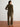 Woman wearing an olive green velvet outfit standing against a white wall.