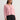 Woman wearing a pink coco cardigan by Margaret O'Leary over a black pleated skirt on a light gray background