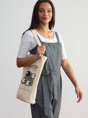 A canvas totebag featuring the Margaret O'Leary logo and an illustration of sheep leaping across a field.