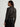 Person wearing a dark gray cardigan over a black outfit on a plain background