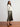 Woman wearing a white sweater and pleated skirt on a plain background