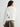 Woman wearing a white sweater with black snowflake patterns on a plain background