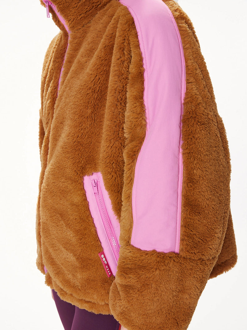 Woman wearing a faux fur brown jacket with pink trim.