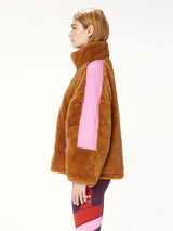Woman wearing a faux fur brown jacket with pink trim.