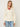 Woman wearing a Leigh Zip Cardigan by Margaret O’Leary, an ivory cable-knit zip cardigan with wide collar styled over a red top and jeans.