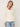 Woman wearing a Leigh Zip Cardigan by Margaret O’Leary, an ivory cable-knit zip cardigan with wide collar styled over a red top and jeans.