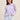 Woman wearing a lilac washed Tie Dye Longsleeve by Margaret O'Learywith white pants against a plain background