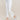 Person wearing white Stretch Twill Cropped Flare Pants and silver shoes on a beige background