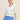 Woman wearing a white Puff Short Sleeve Pullover sweater and blue polka dot skirt by Margaret O'Leary on a beige background