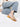 Person wearing blue striped pants and tan Intentionally Blank sandals on a white background