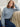 Woman wearing a Thermal Sweatshirt, a blue sweater sitting on a beige couch.
