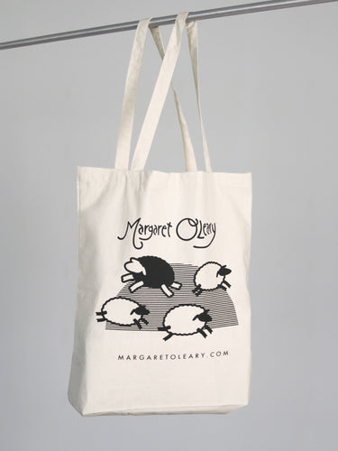 A canvas totebag featuring the Margaret O'Leary logo and an illustration of sheep leaping across a field.