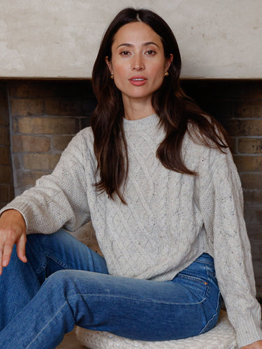 Woman wearing a grey cable knit sweater.