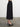 Woman wearing a Natalya Pleated Skirt by Margaret O’Leary, a black pleated midi skirt styled with a printed silk cami on a plain background.