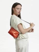 Woman carrying the Mini Light Shoulder Bag in Orange by Jack Gomme.