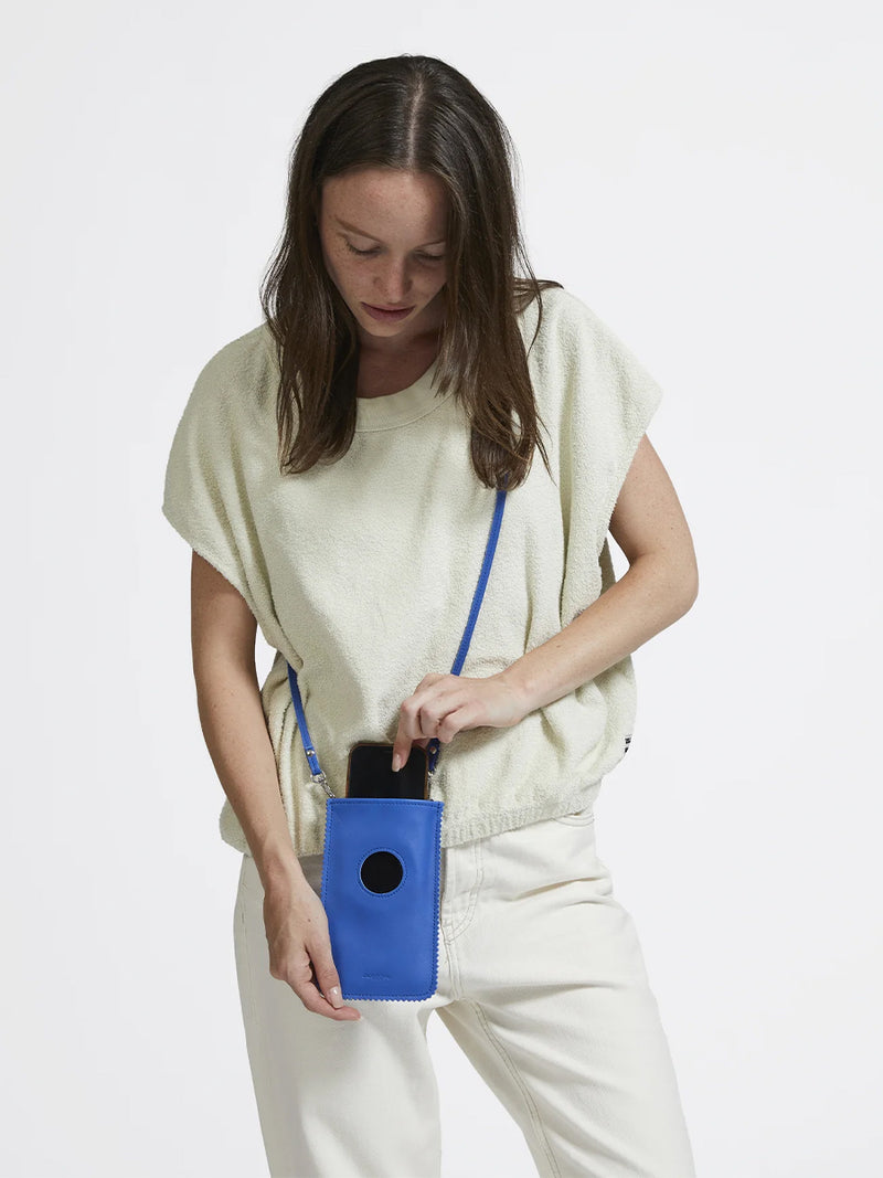 Woman carrying the Niki Leather Phone Case in Blue by Jack Gomme. 