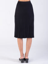 Model wearing a pleated black skirt.