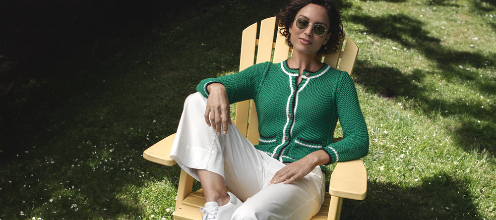 Woman sitting on a yellow lawn chair wearing the Jordan Cardi in Palm mix by Margaret O'Leary.