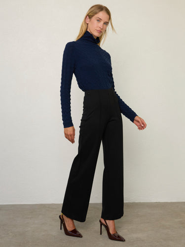 Person wearing the Dimensional Neck, a navy tneck textured sweater by Margaret O'Leary paired with black pants.