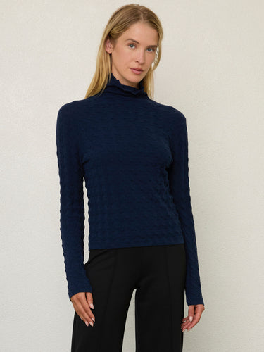 Person wearing the Dimensional Neck, a navy tneck textured sweater by Margaret O'Leary paired with black pants.
