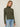 Person wearing the Dimensional Neck, a green tneck textured sweater by Margaret O'Leary paired with blue jeans.