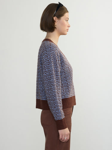 Side view of a person wearing the Jacquard Vee, a brown and blue patterned sweater by Margaret O'Leary paired with brown pants
