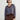 Person wearing the Jacquard Vee, a brown and blue patterned sweater by Margaret O'Leary paired with brown pants