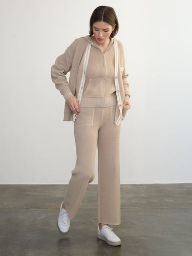 Person wearing the Joan Waffle Pant, a beige waffle knit pant by Margaret O'Leary paired with a matching hoodie and cardigan