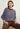 Woman wearing the Lola Pullover, a striped sweater by Margaret O'Leary and brown pants sitting on a white background