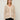 Person wearing the Santa Rosa Cardi a beige cardigan with white accents by Margaret O'Leary paired with plaid pants