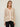 Person wearing the Santa Rosa Cardi a beige cardigan with white accents by Margaret O'Leary paired with plaid pants