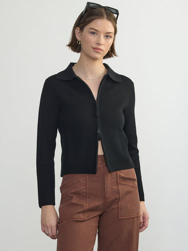 Person wearing the St. Carmel a black waffle knit zip up polo by Margaret O'Leary paired with brown pants.
