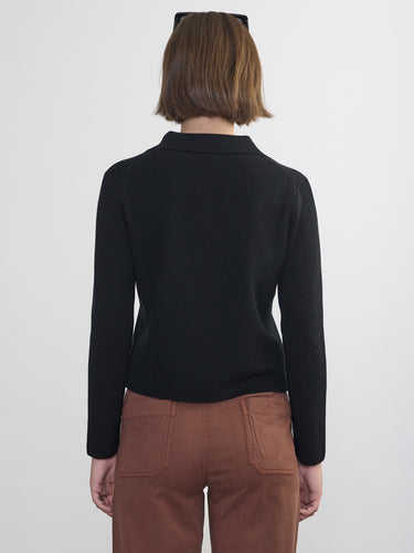Person wearing the St. Carmel a black waffle knit zip up polo by Margaret O'Leary paired with brown pants.