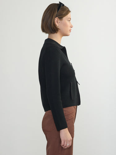 Person wearing the St. Carmel a black waffle knit zip up polo by Margaret O'Leary paired with brown pants.