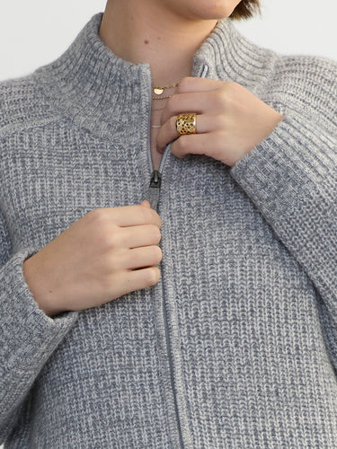 Person wearing the Tahoe Zip Up, a grey tneck cashmere zip up by Margaret O'Leary paired with blue jeans.