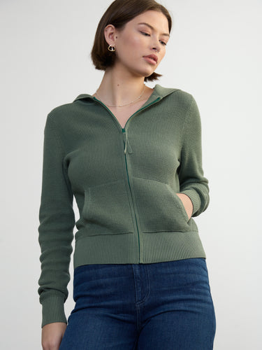 Person wearing the Thermal Hoodie a green waffle knit zip up hoodie by Margaret O'Leary paired with blue jeans.