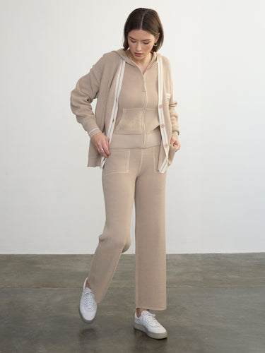 Person wearing the Joan Waffle Pant, a beige waffle knit pant by Margaret O'Leary paired with a matching hoodie and cardigan

