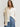 A woman wearing a white Drapey Twill Shirt and blue-patterned Venice Skirt by Margaret O'Leary on a plain background